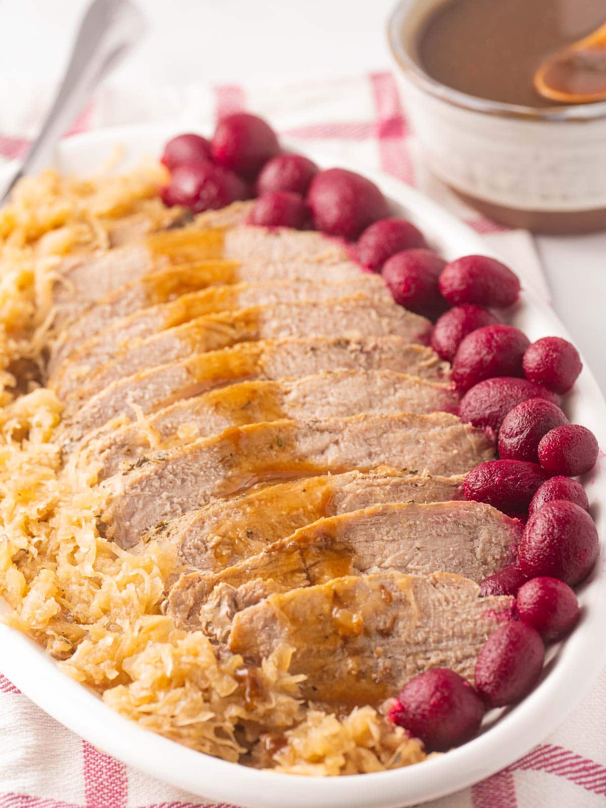 Sliced pork tenderloin with gravy, sauerkraut and beets on platter.