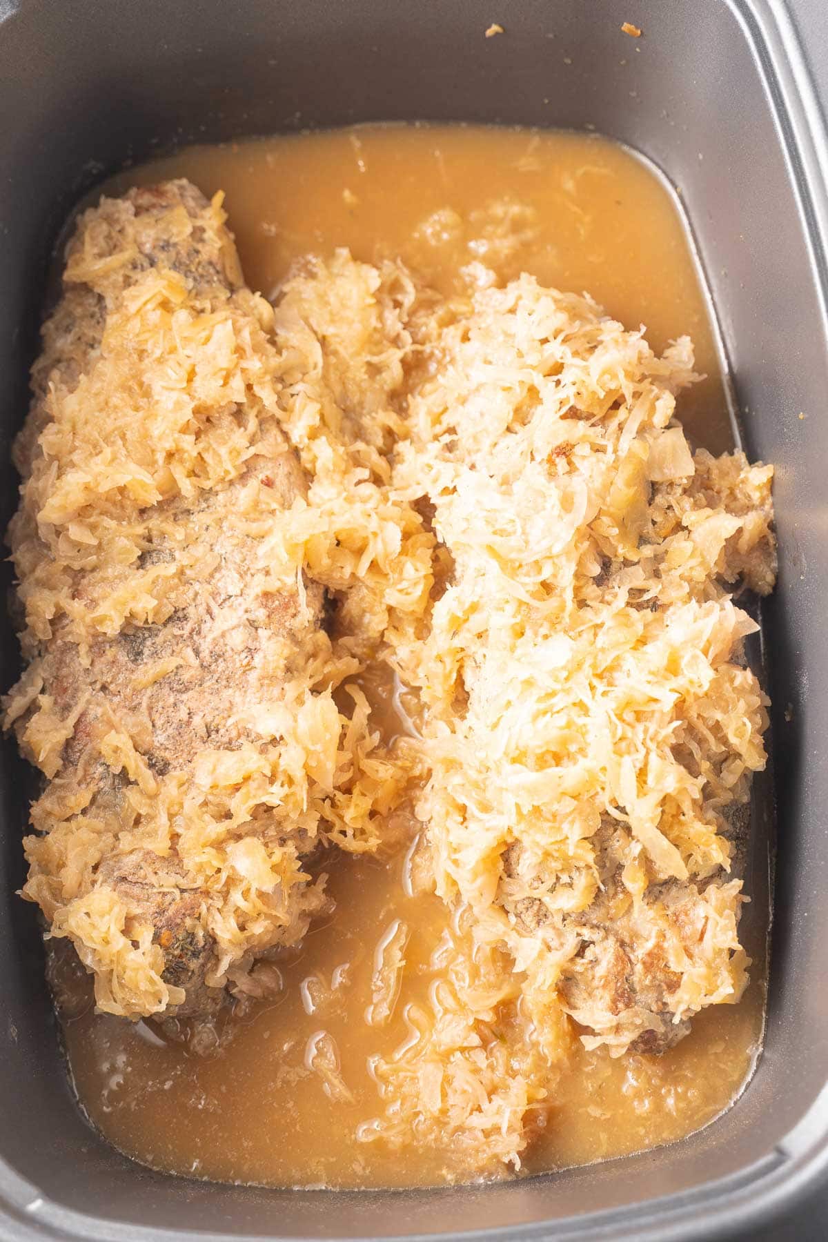 Pork tenderloin, sauerkraut and applesauce in slow cooker.