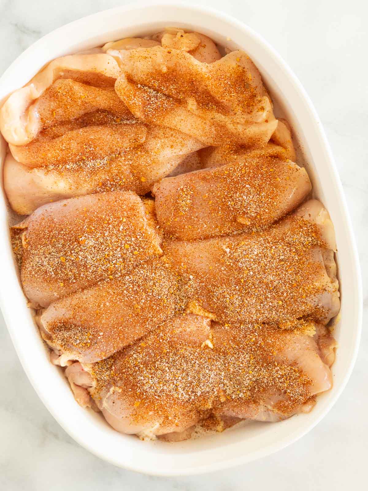 Seasoned boneless chicken in white bowl.