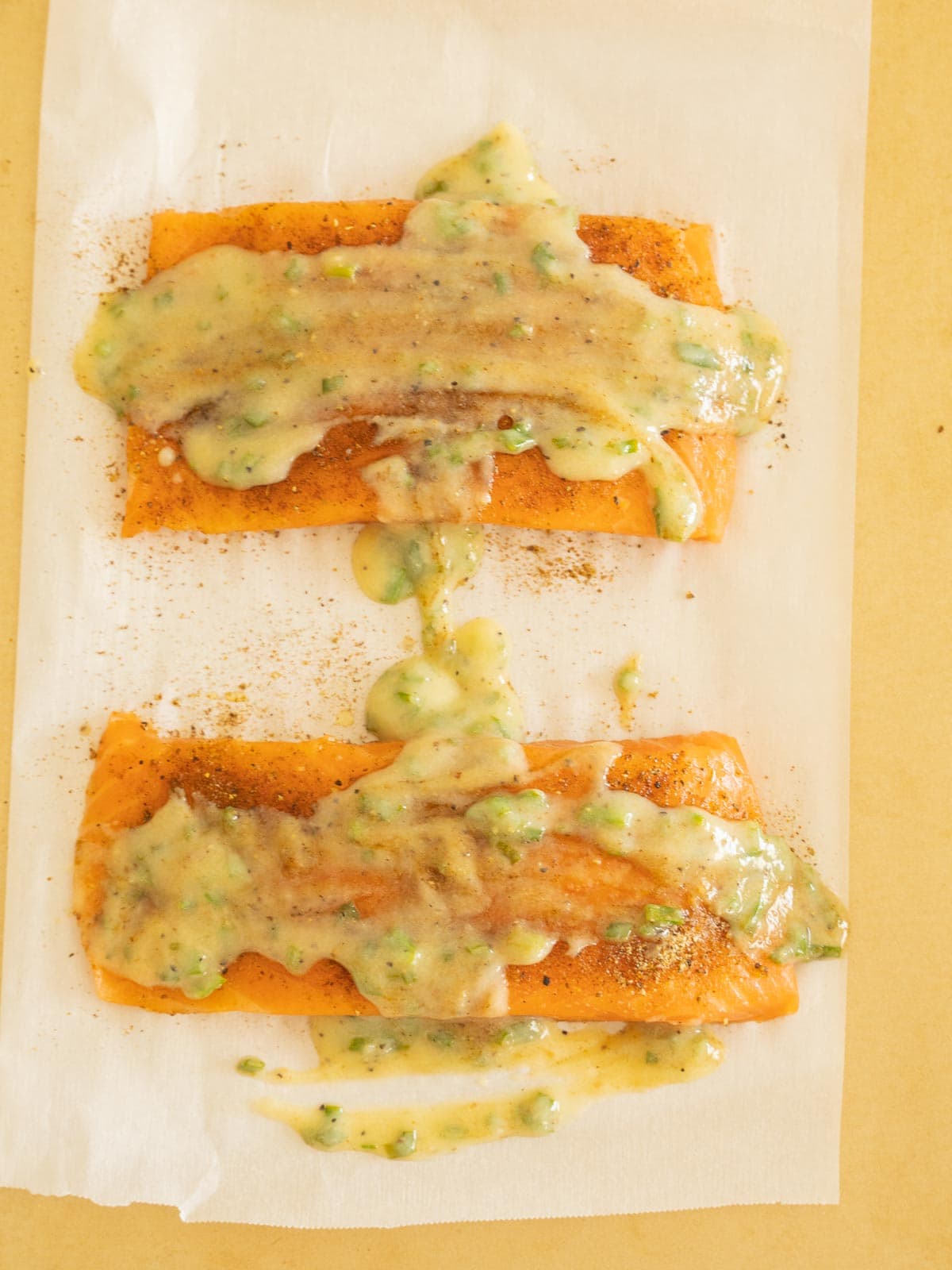 Salmon fillets with lemon chive sauce on parchment.