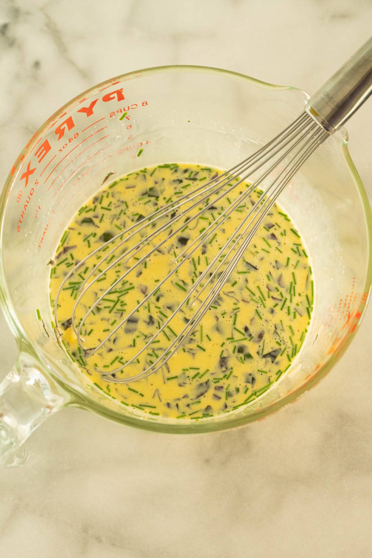 Bowl of whisked eggs, basil, seasonings.