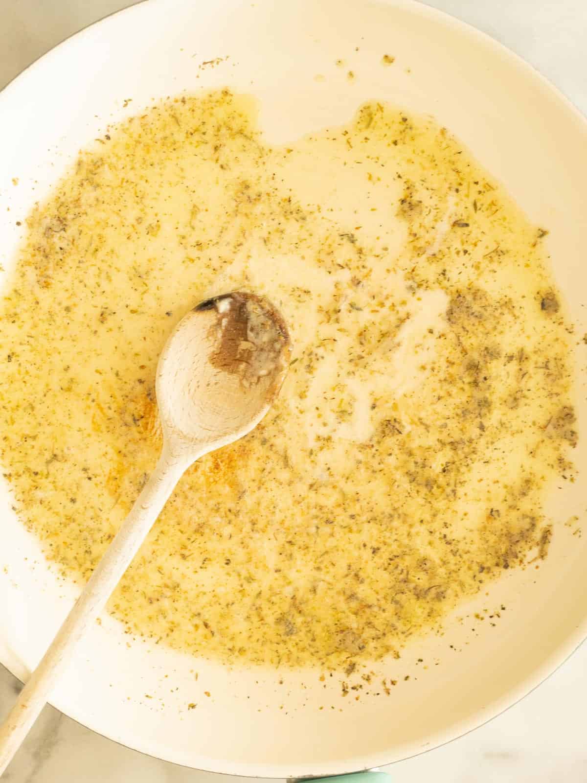 Garlic, butter, seasonings in skillet with wooden spoon,