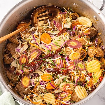 Kung pao pork in large skillet with spoon.
