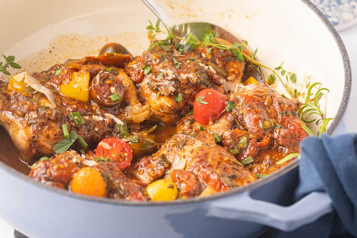 Boneless chicken thighs, burst cherry tomatoes, thyme stems in large pot
