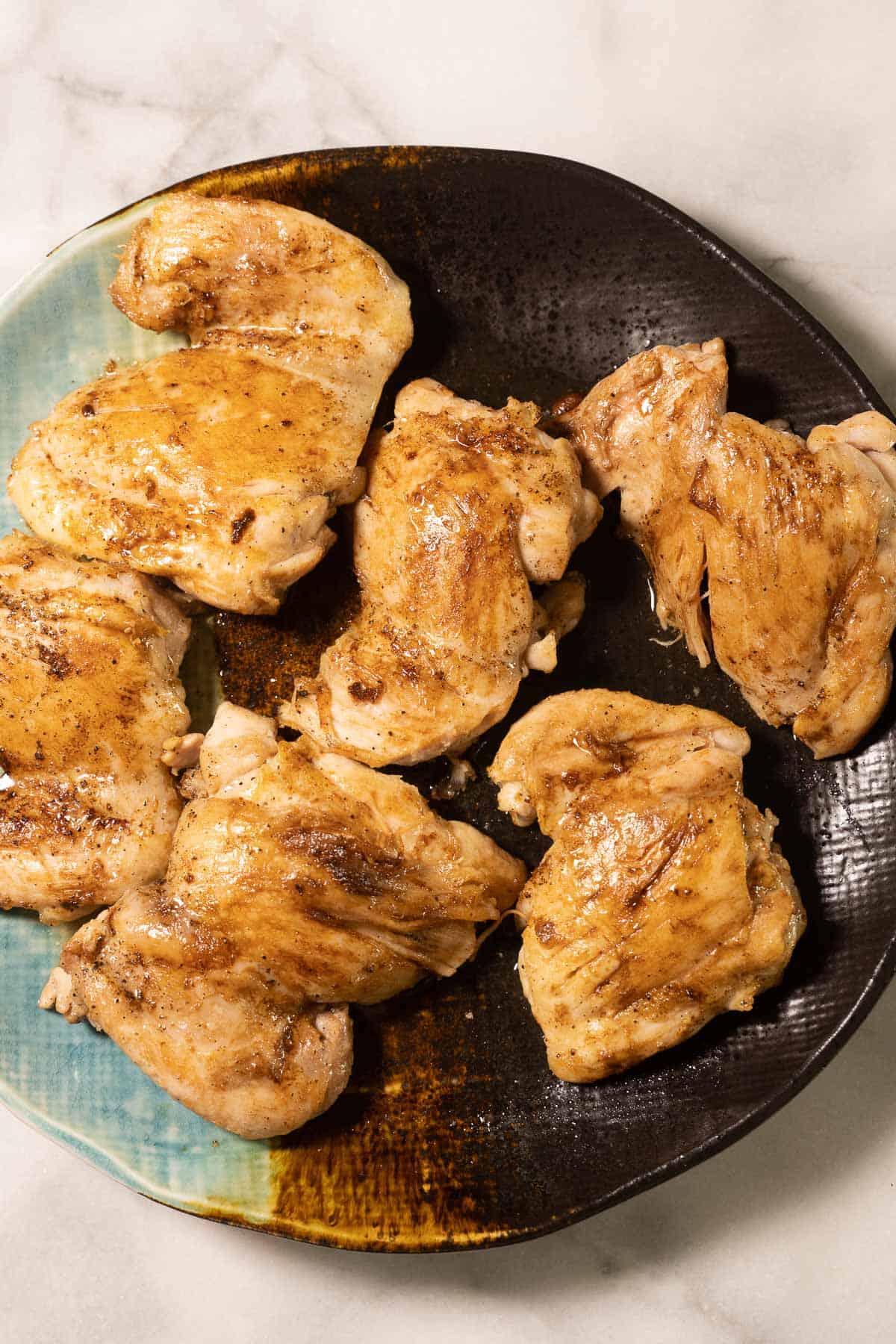 Sauteed boneless chicken thighs on plate.