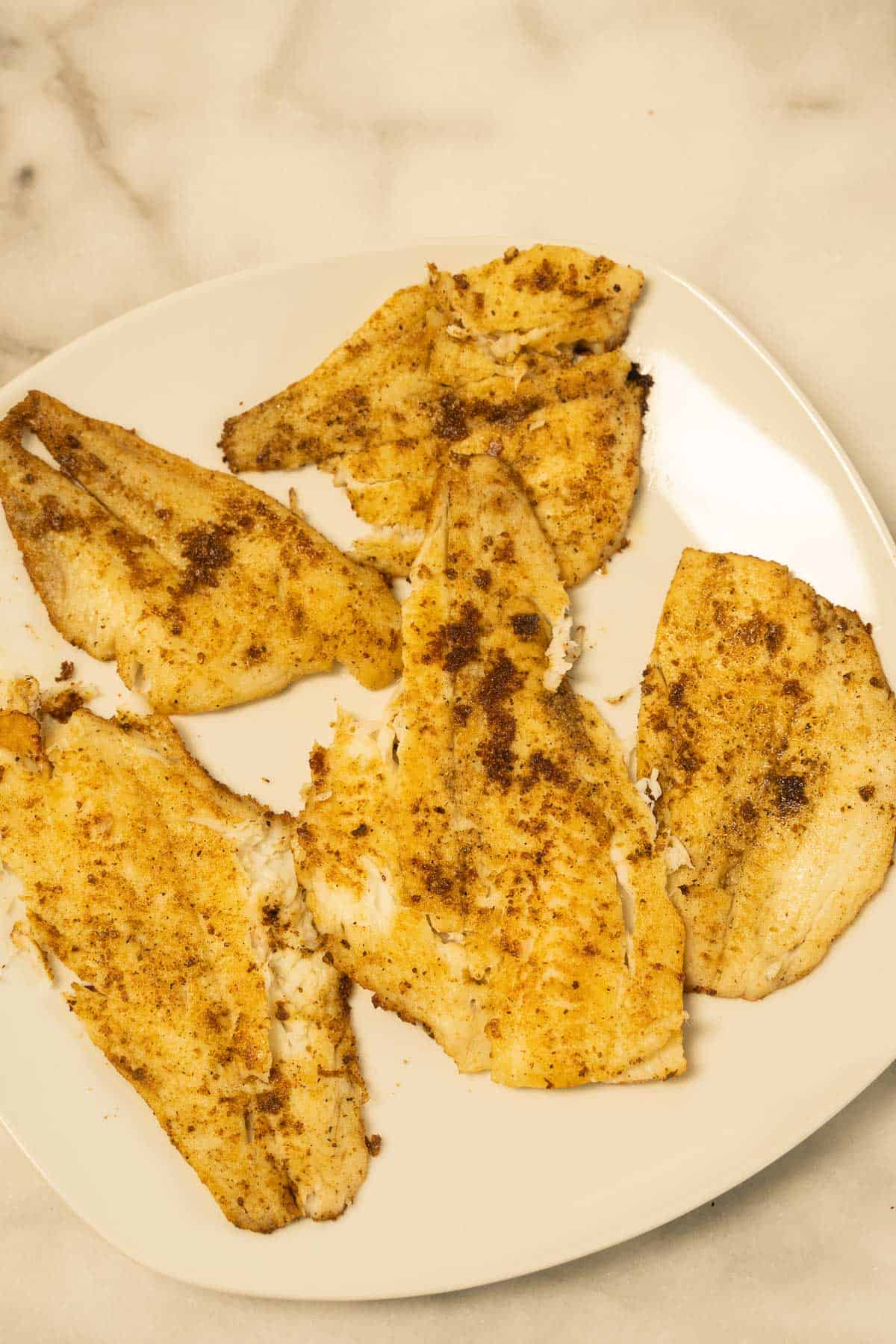 Pan fried flounder fillets on white platter.