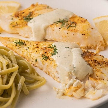 Baked Orange Roughy with Wasabi lemon sauce and spinach fettucine on plate.