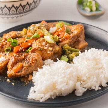 Slow Cooker Mongolian Pork with white rice on black plate.