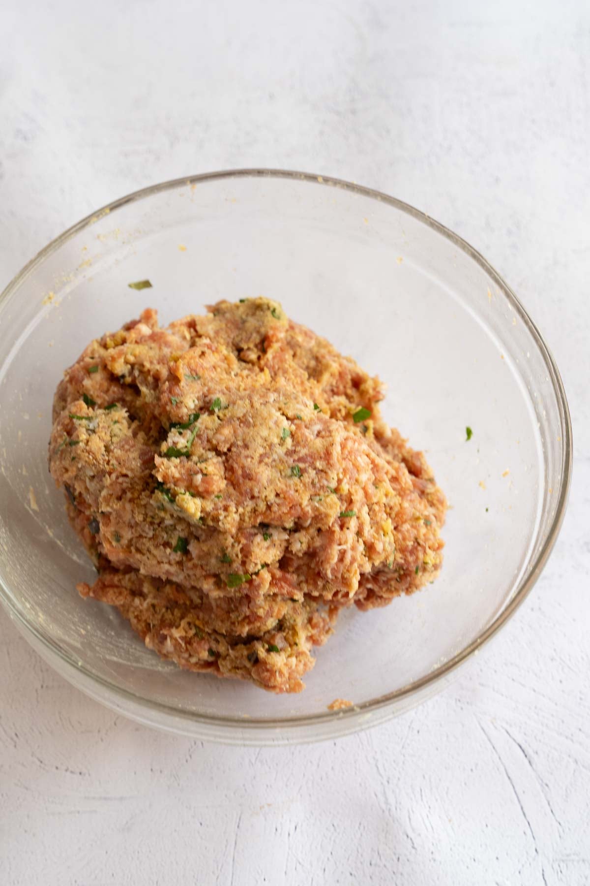 ground sausage meatball mixture in glass bowl.