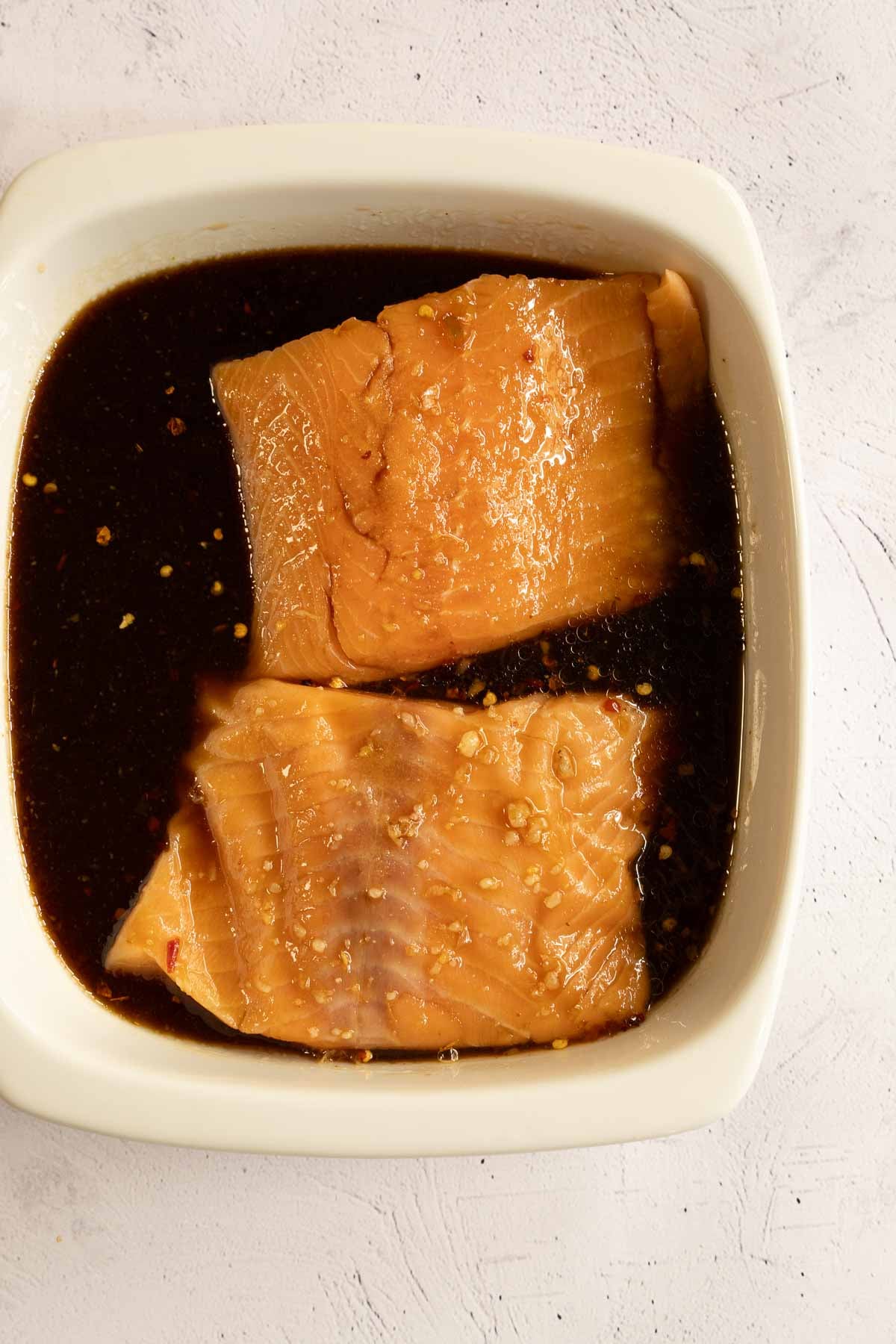Salmon fillets marinating in bowl.
