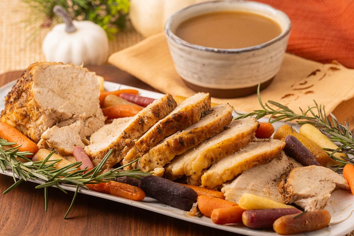 Sliced Roasted Boneless turkey breast with carrots and gravy.