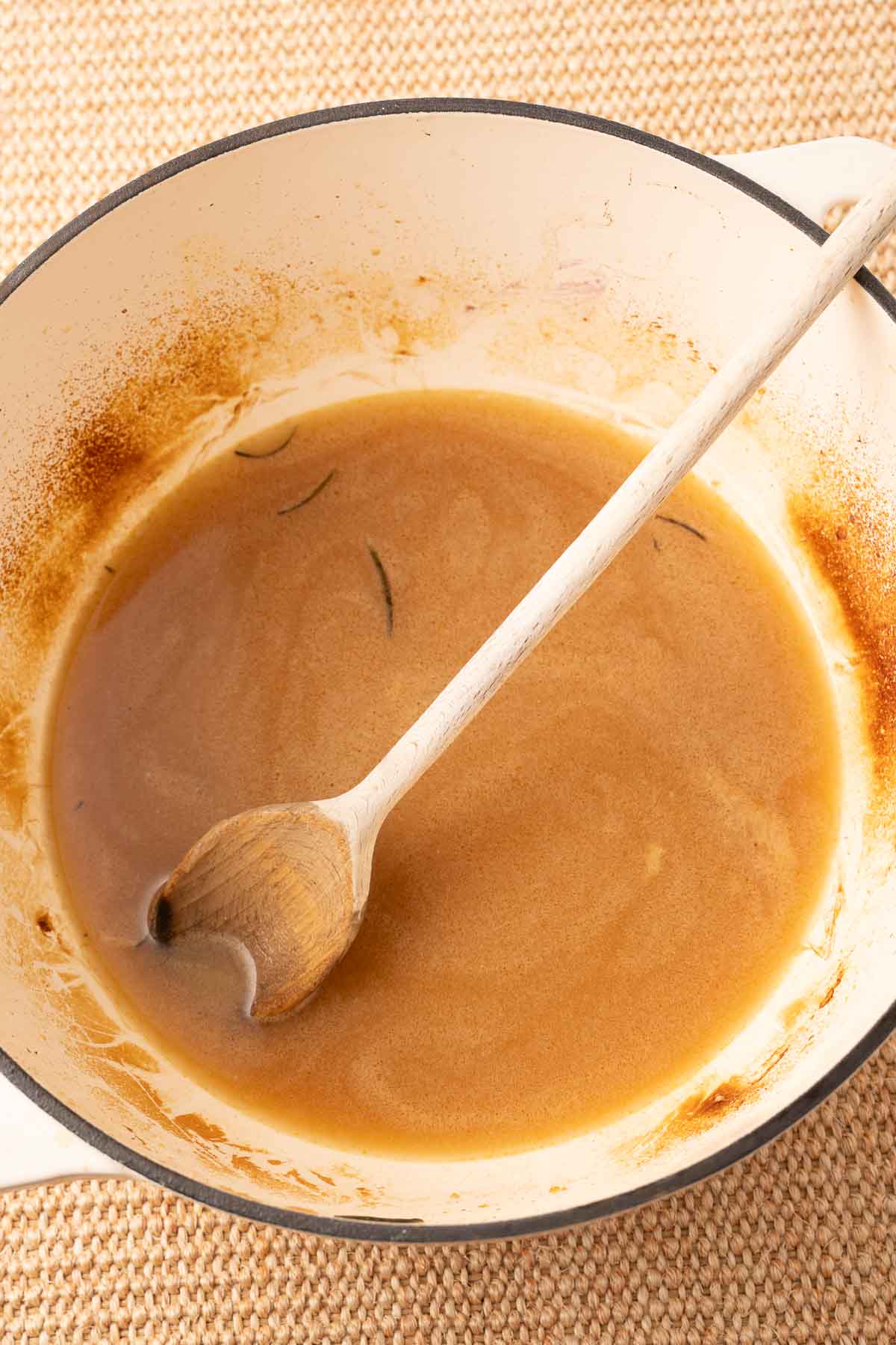 Turkey gravy in dutch oven with wooden spoon.
