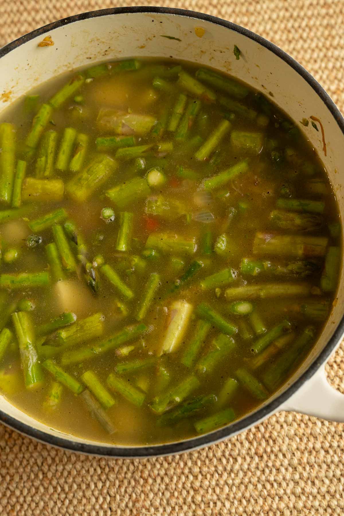 Asparagus, potatoes, red pepper with. chicken stock in large white pot