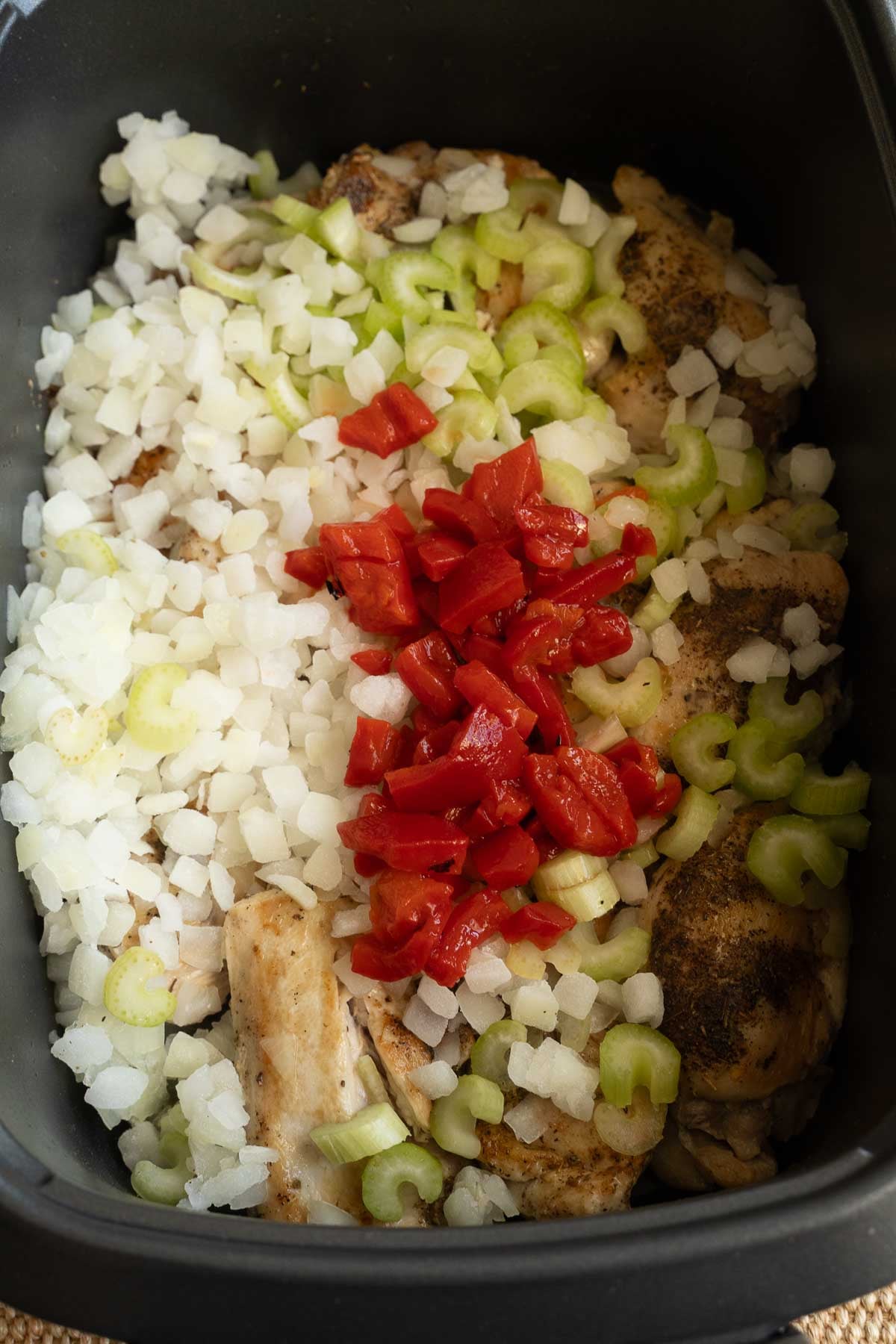 Onions, red pepper, chicken in slow cooker.
