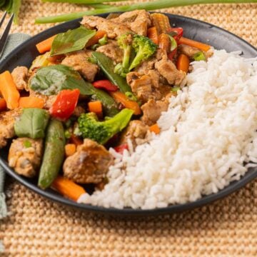 Thai Basil Pork with vegetables and rice on plate.