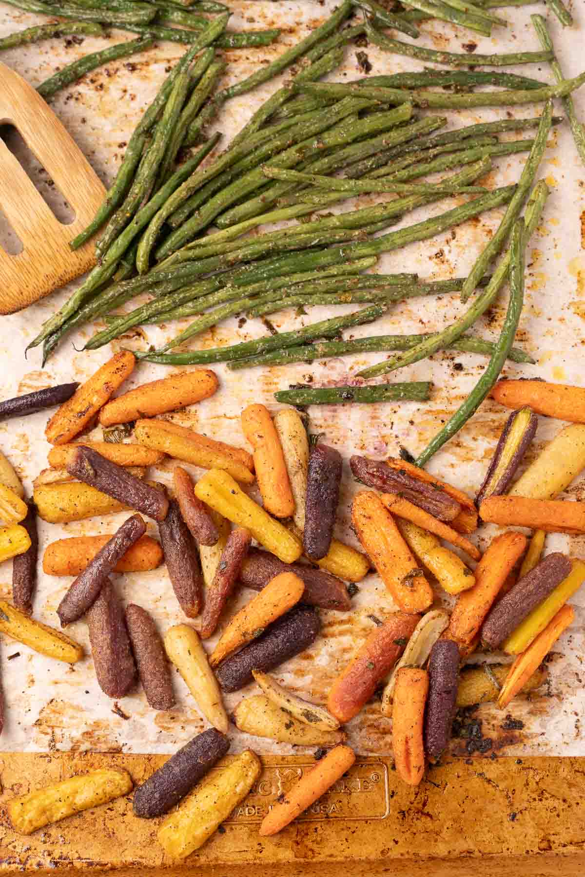 Seasoned baby carrots and green beans on baking tray.