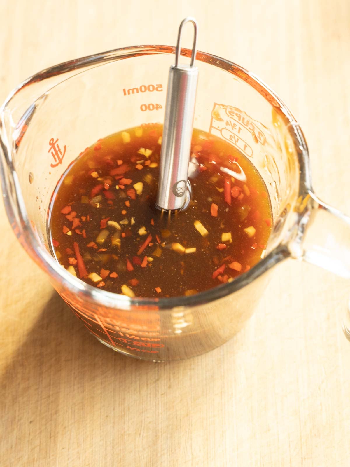 Stirring sauce ingredients in glass cup.