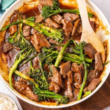 Beef and Broccolini Stir Fry in skillet with wooden spoon.