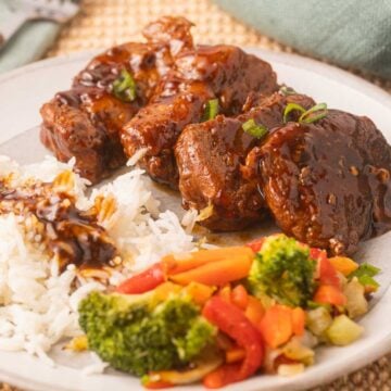 Pork tenderloin medallions with rice, sauce and vegetables on plate.