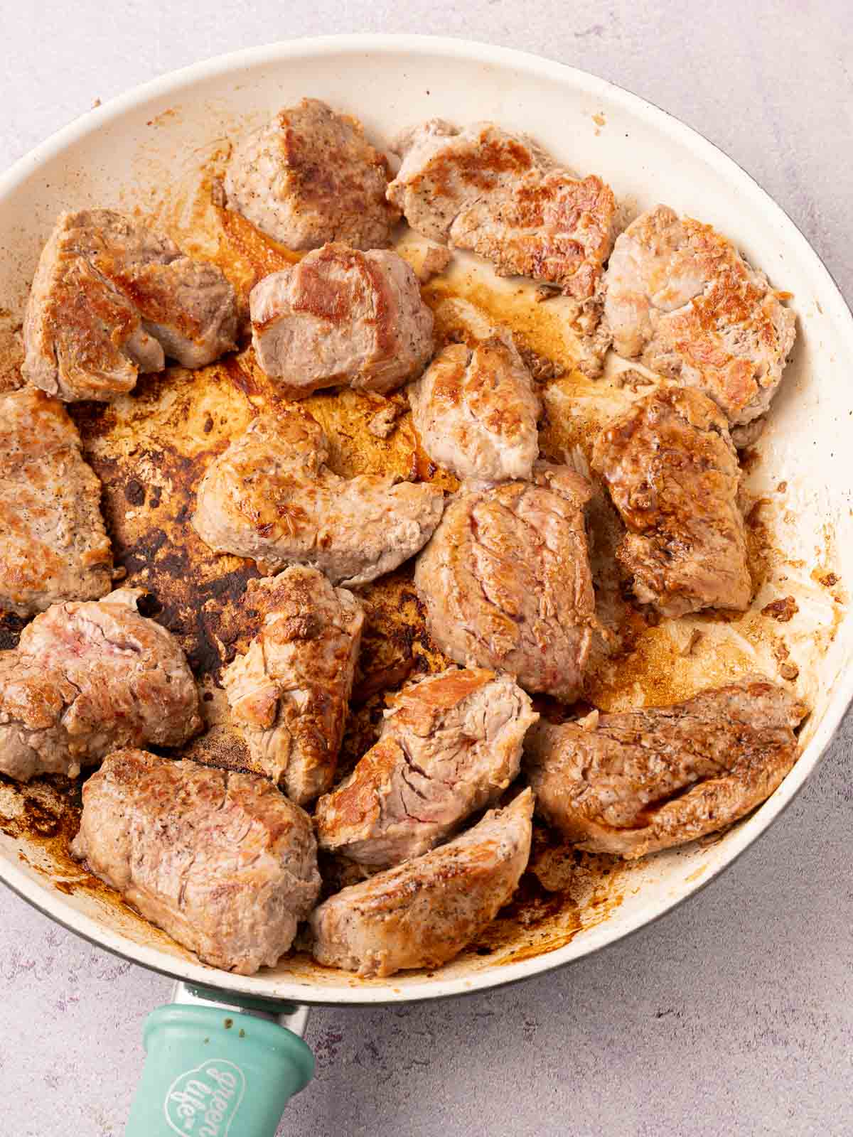 Browned pork tenderloin medallions in skillet.