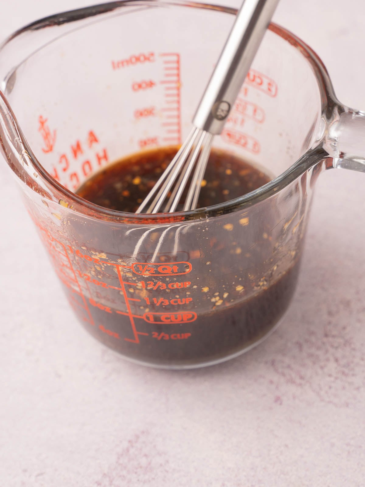 Teriyaki sauce in glass cup with whisk.