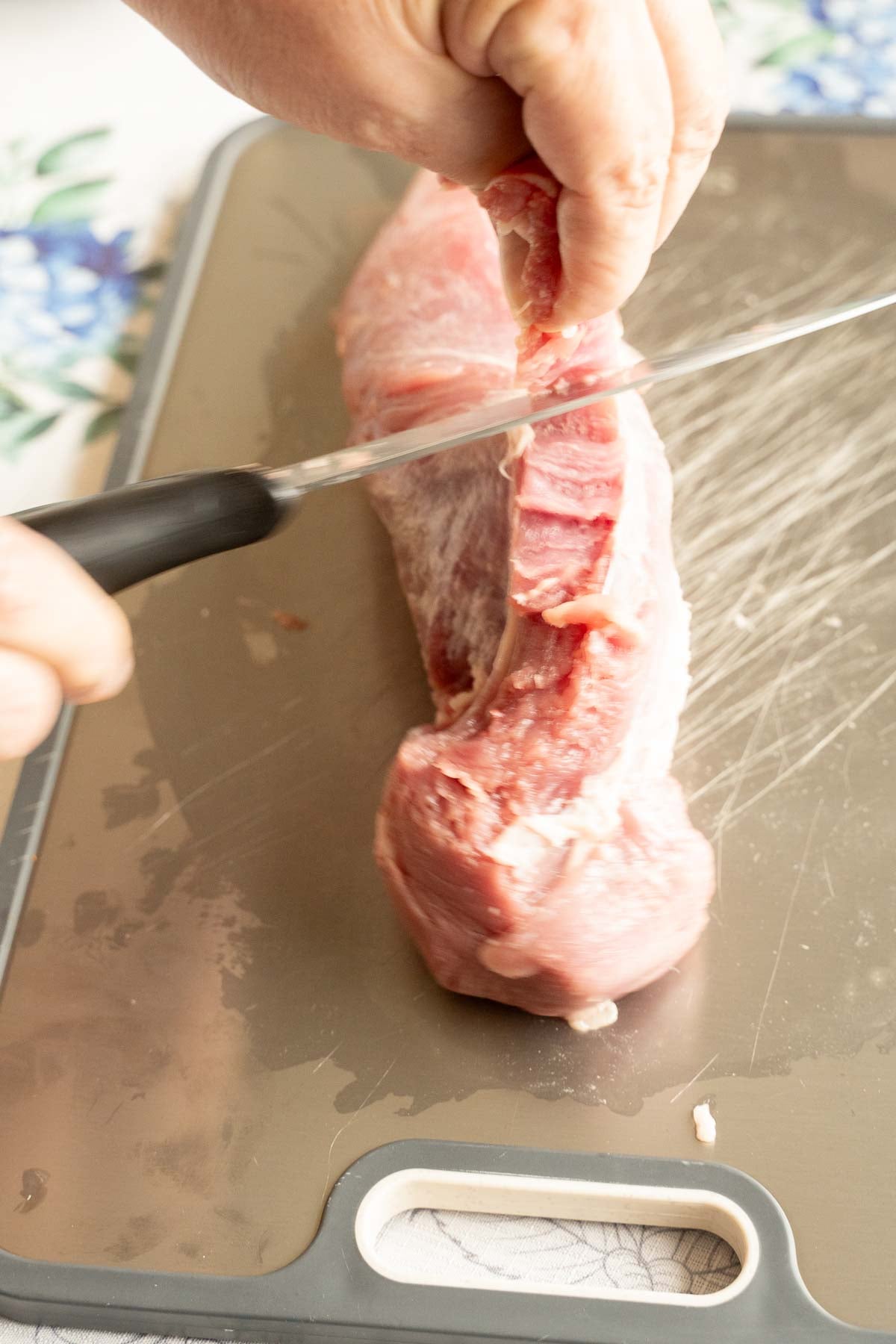Removing silver skin on top of pork tenderloin.