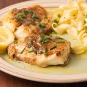 Air Fried Seasoned Atlantic haddock fillets with lemon chive sauce and wide egg noodles on plate.