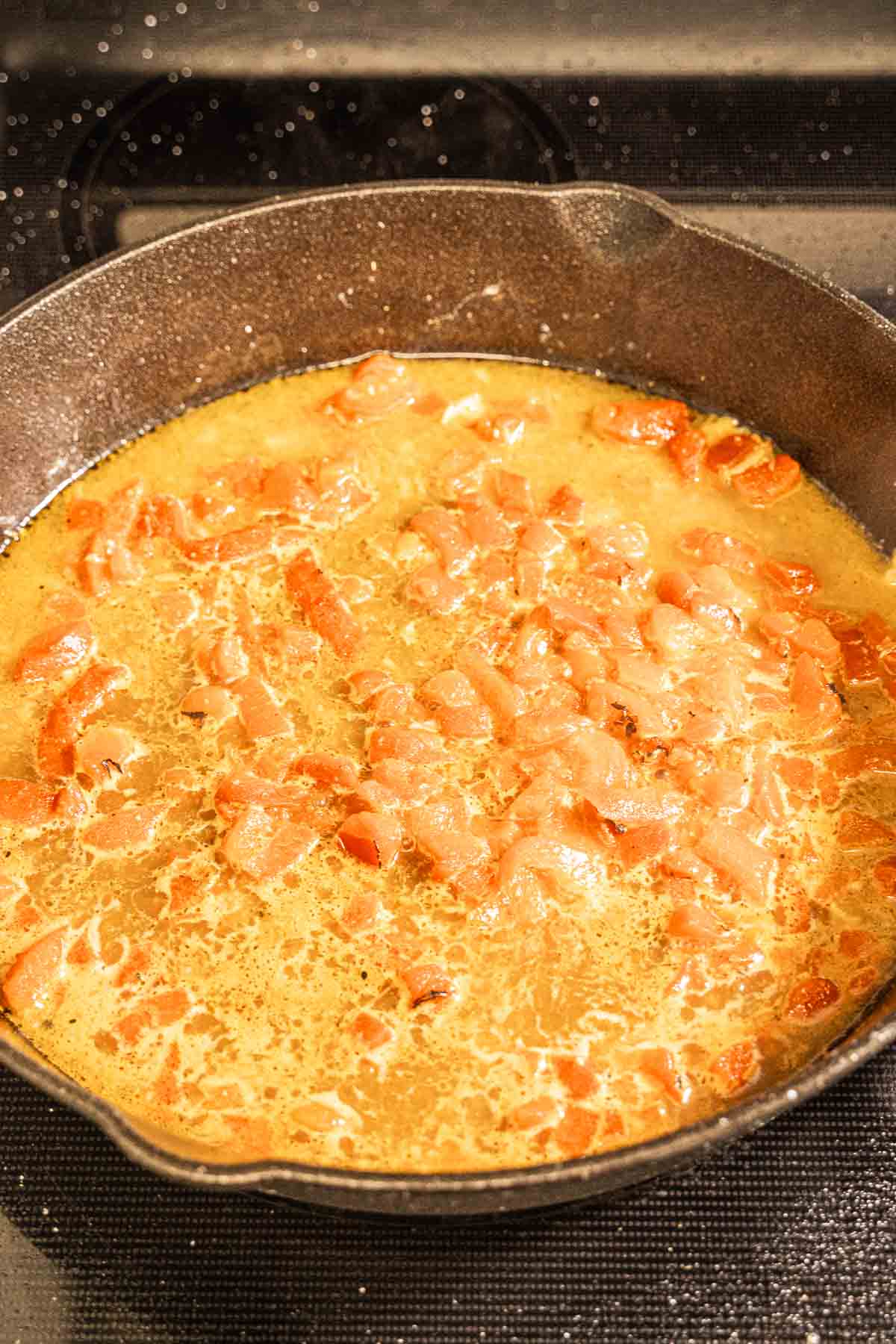 Chicken broth and seasonings added to red peppers in skillet.