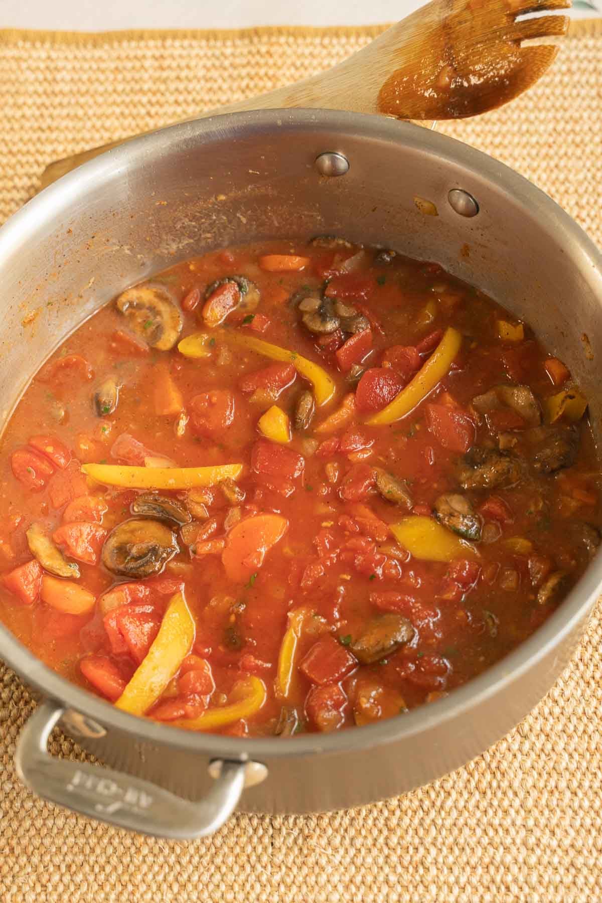 Adding wine and tomatoes to vegetables in skillet.